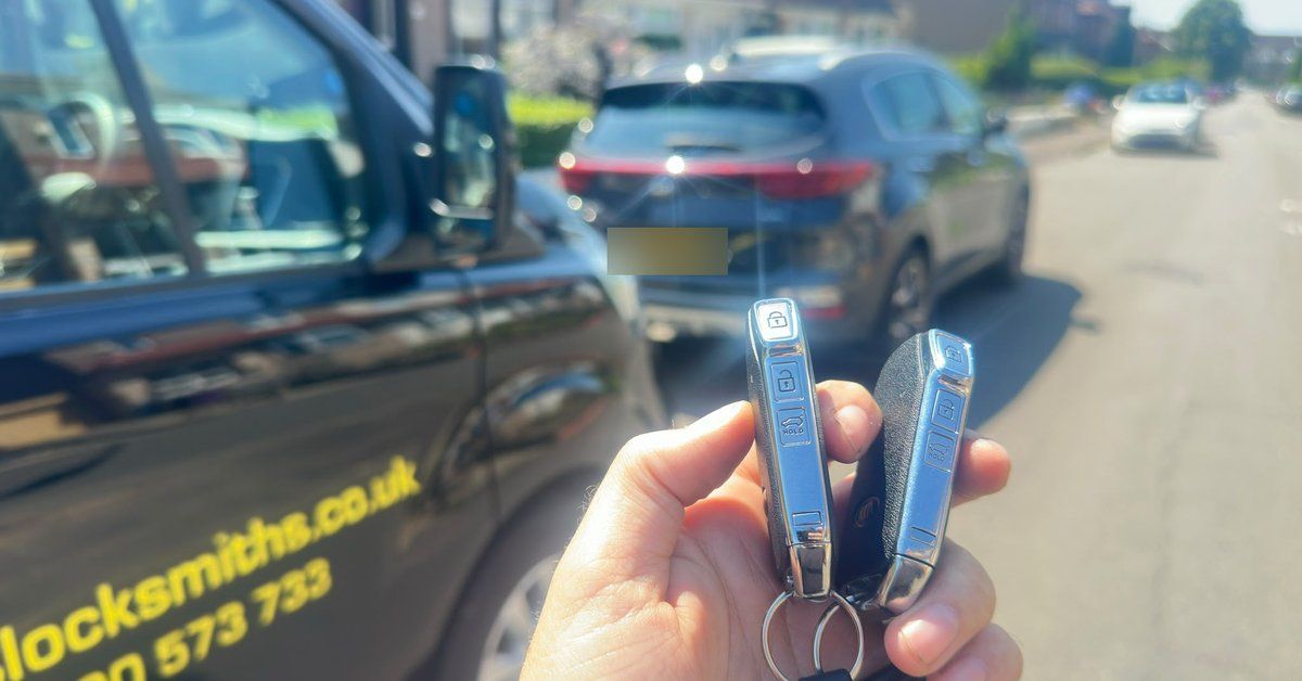 Two Kia smart keys held next to the LKC Locksmiths van